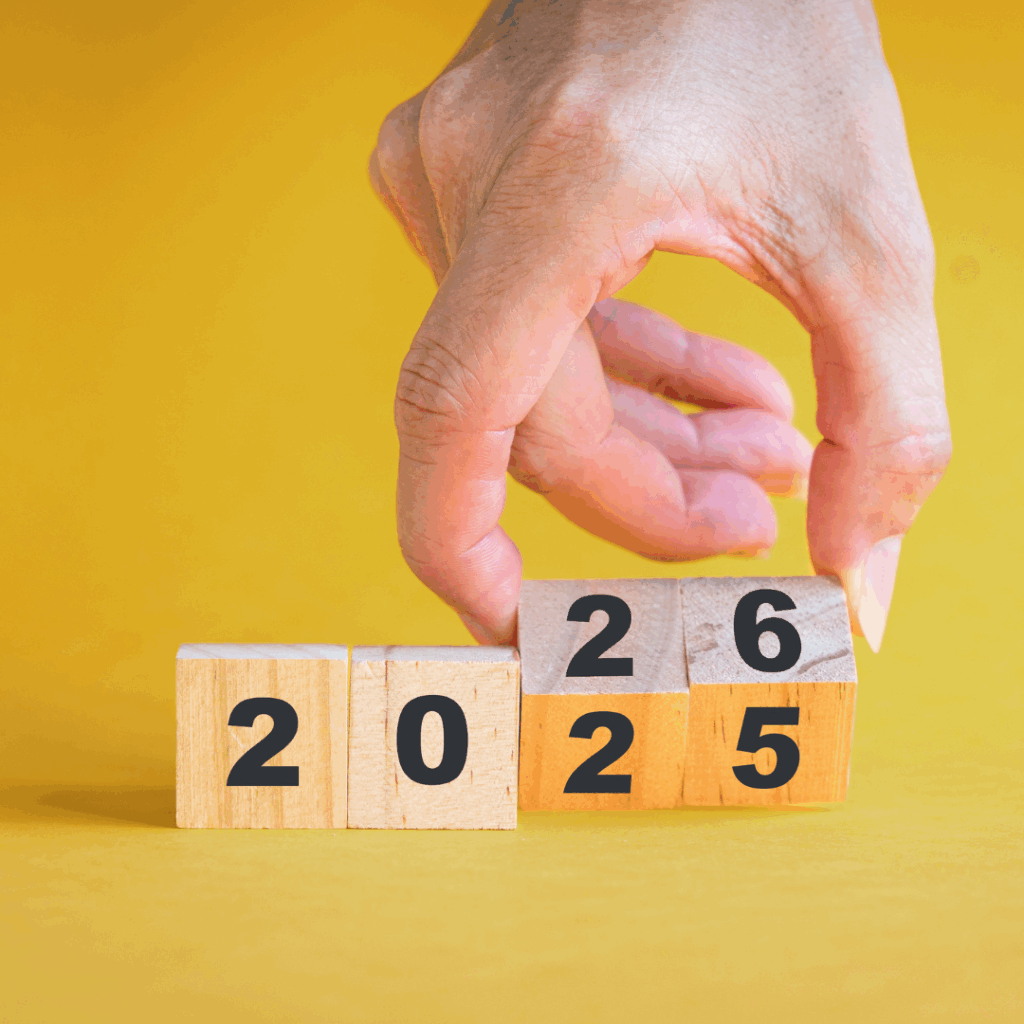 Hand flipping wooden blocks from 2025 to 2026 on a yellow background, symbolizing leaving the past behind and starting fresh in the new year