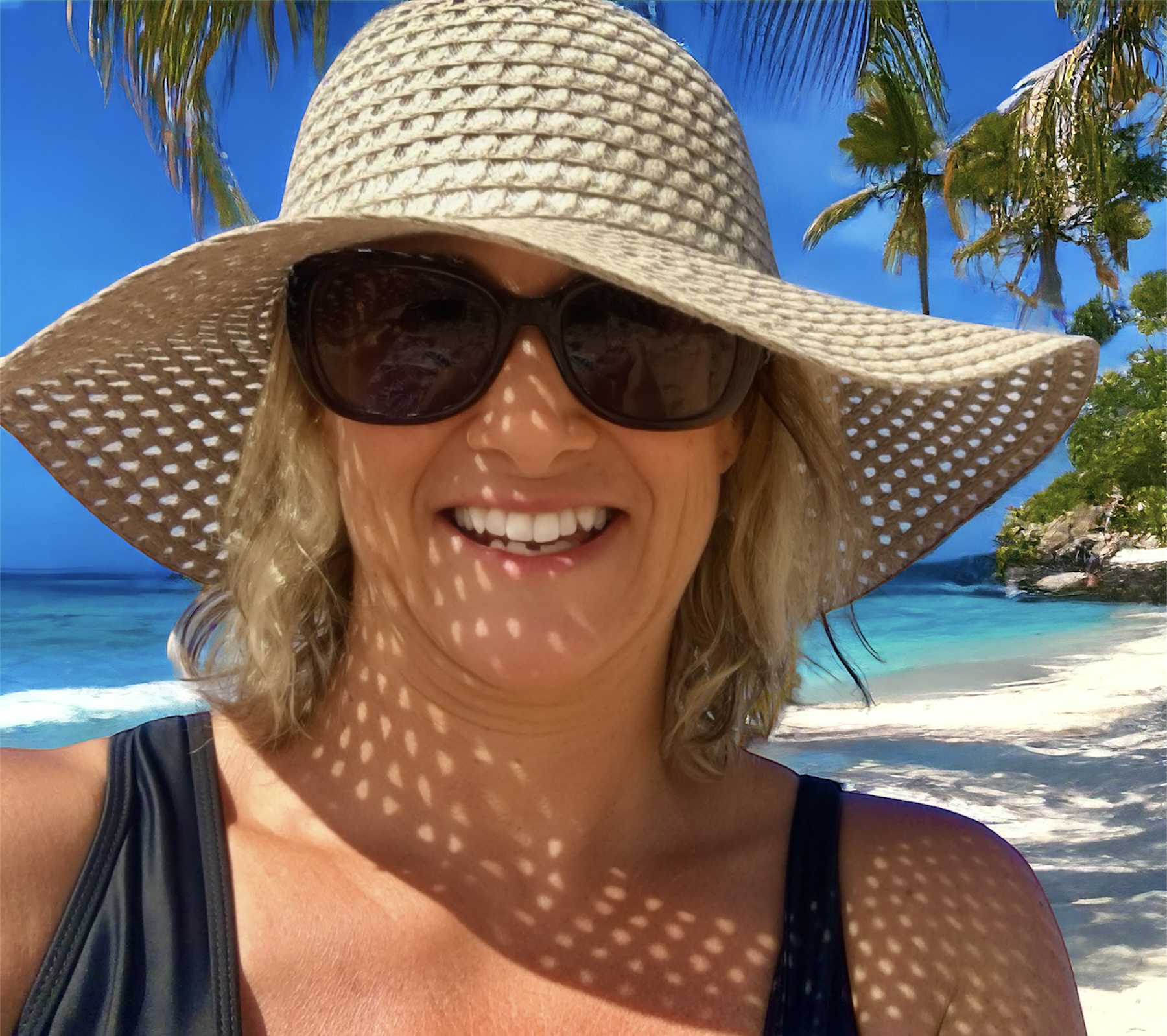 Smiling woman in a wide-brimmed sun hat and sunglasses on a tropical beach, symbolizing freedom and lifestyle after transitioning out of corporate.