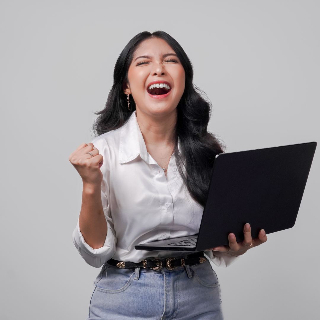 A confident professional woman celebrating with joy while holding a laptop, representing clarity, confidence, and empowerment during her career transition from corporate to entrepreneurship.